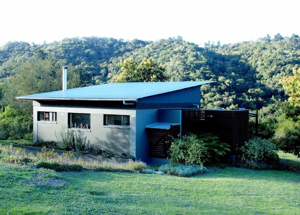 Modern blue and white cottage with sloped roof nestled among forested hills