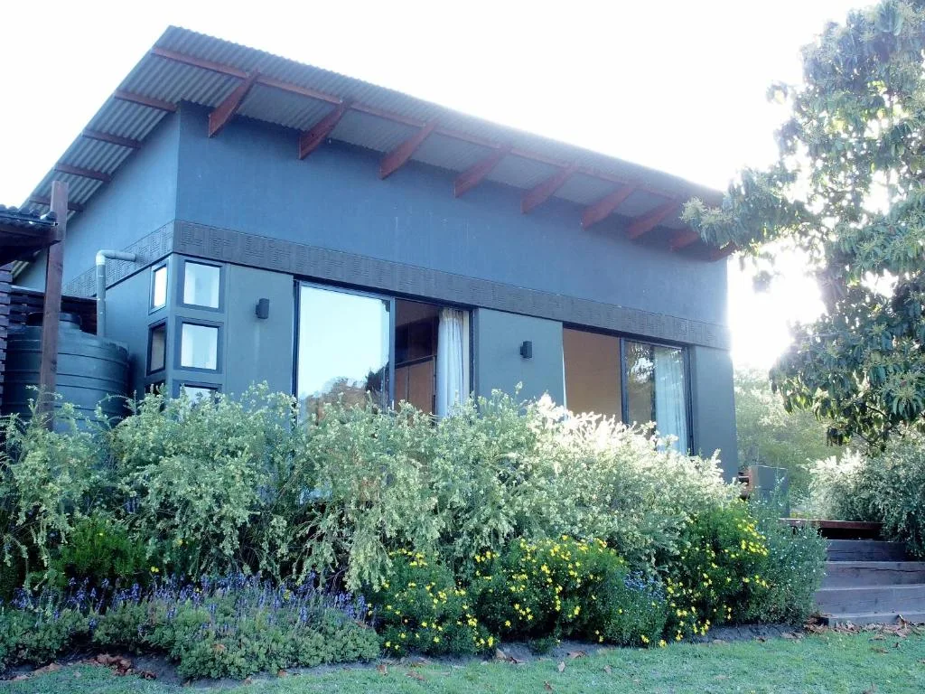 Modern blue cottage with large windows and lush flowering garden beds