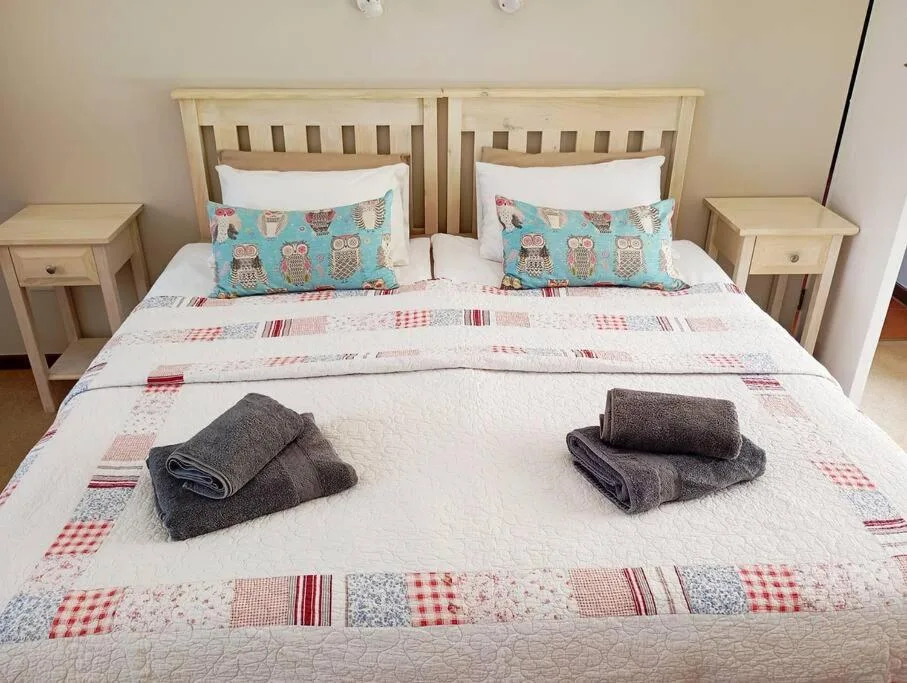 Bright bedroom with twin wooden beds, patchwork quilt, and folded towels