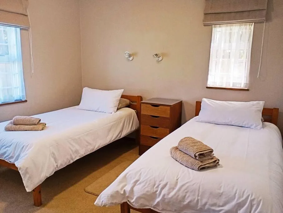 Twin bedroom with two single beds, wooden bedside table, and fresh white linens