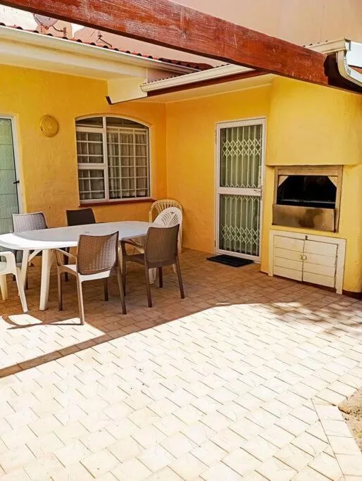 Outdoor patio area with dining table, chairs, and yellow-walled structure