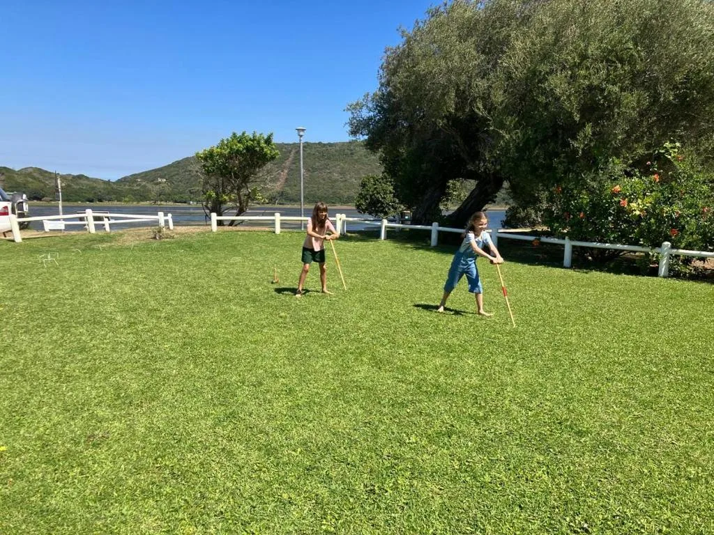 Children playing on manicured lawn with lagoon and mountains behind