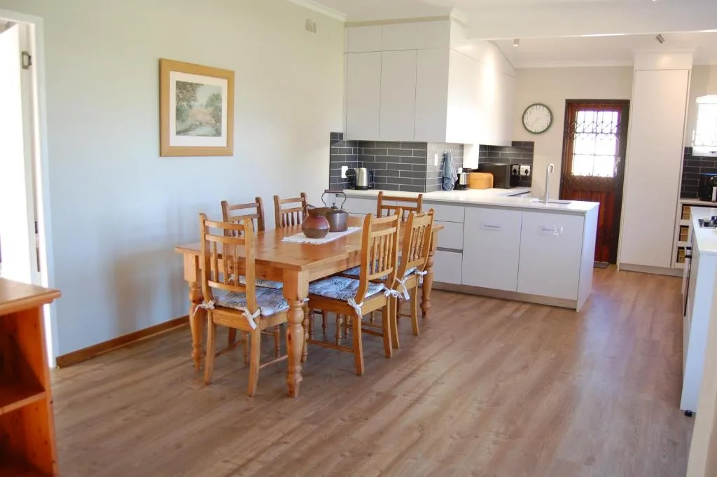 Wooden dining table with six chairs in open-plan kitchen and dining area