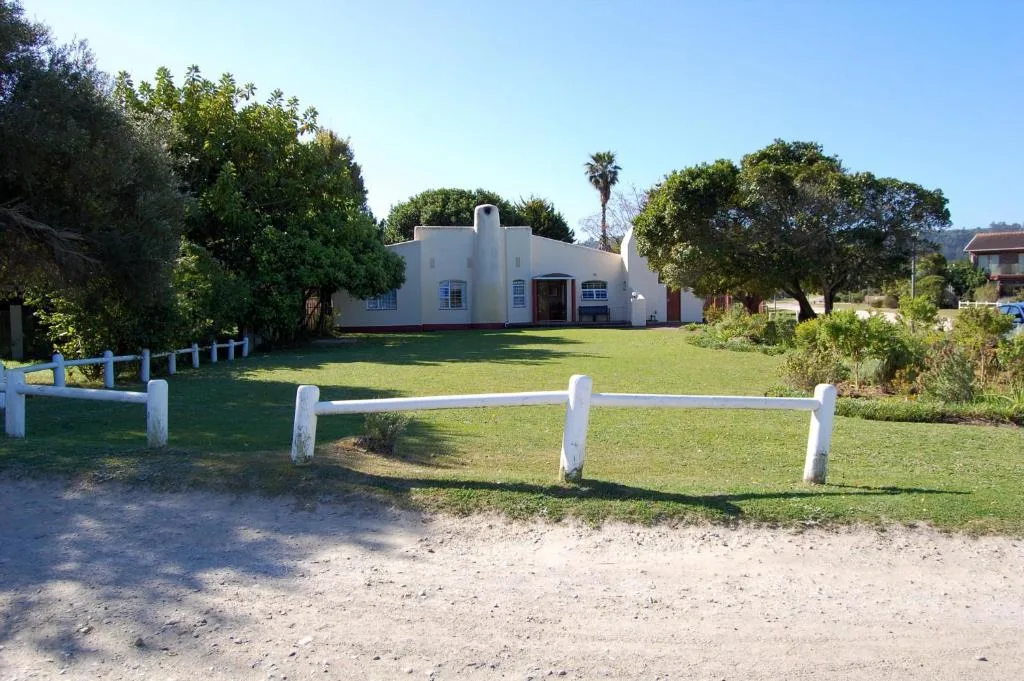 White-walled property with manicured gardens and white fence entrance