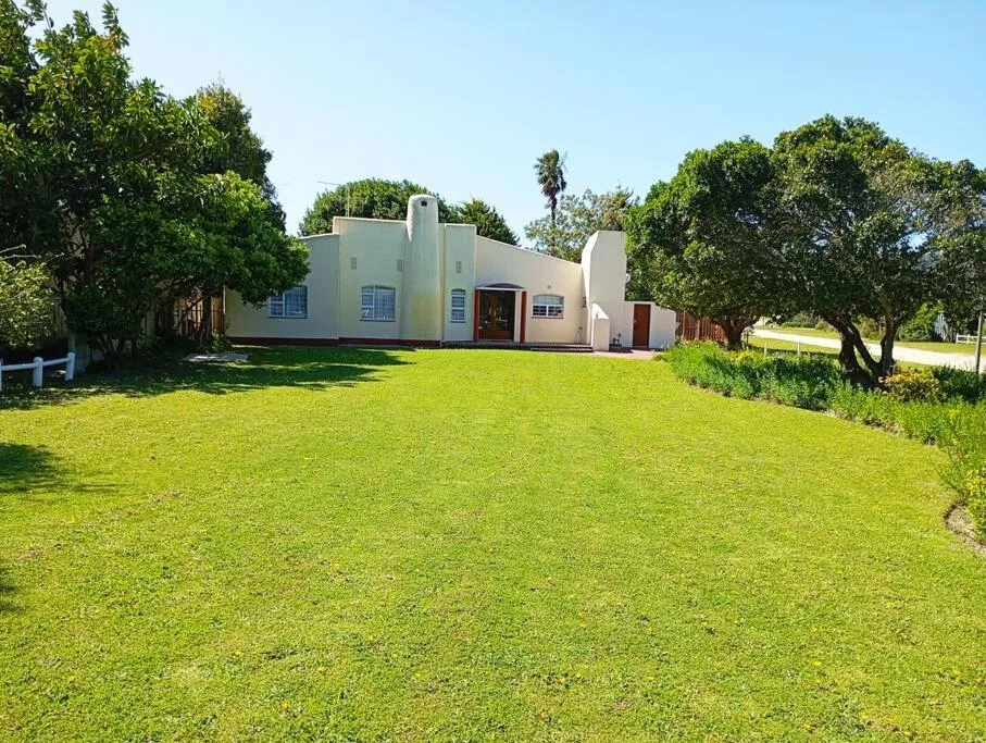 White modernist holiday home with curved walls and manicured green lawn