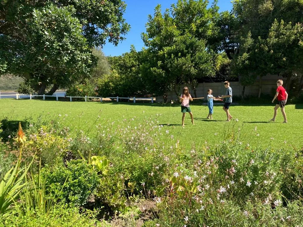 Spacious garden with flowering plants and children playing tug-of-war outdoors