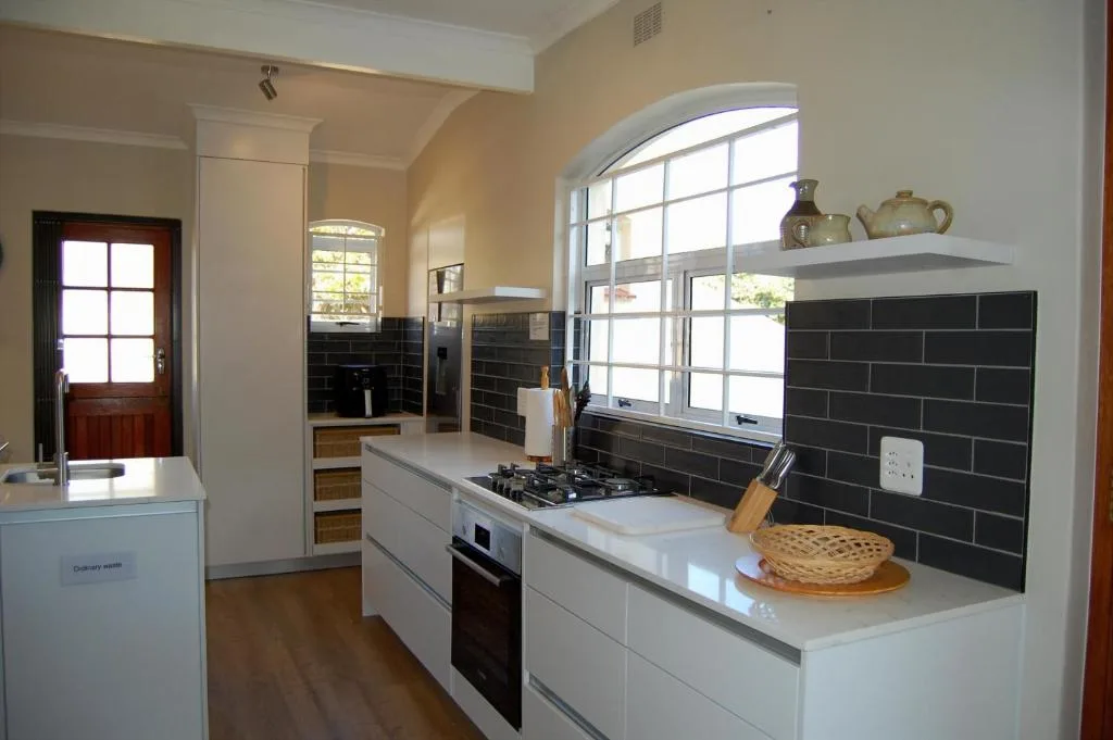 Modern kitchen with white cabinetry, black tile backsplash, and gas cooktop