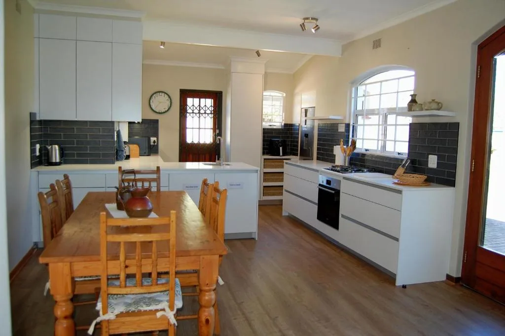 Modern kitchen with white cabinetry, black tile backsplash, and dining table