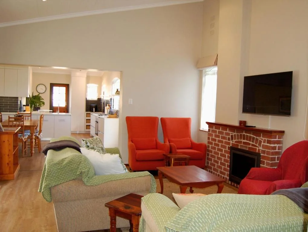 Open-plan lounge with red armchairs, fireplace, and TV wall mount