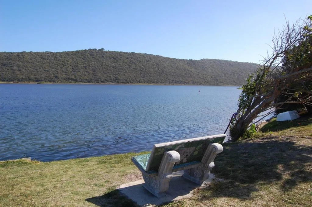 Scenic lakeside view with forested hills and viewing bench overlooking calm water