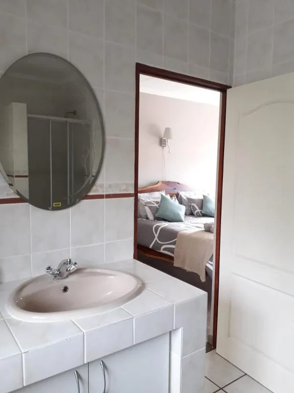 Clean bathroom with round mirror, white sink vanity, and tiled walls