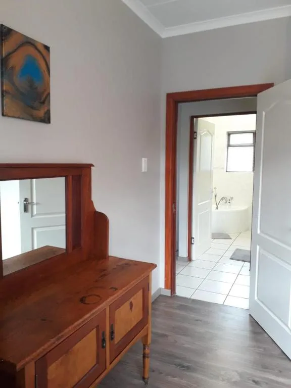Bedroom with wooden dresser, mirror, and doorway to ensuite bathroom