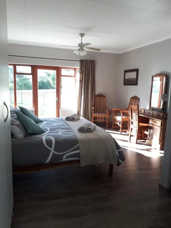 Spacious bedroom with queen bed, glass doors opening to deck, ceiling fan