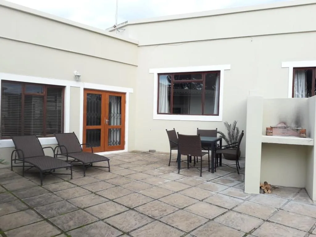 Covered patio with lounge chairs, dining table, and built-in shelving