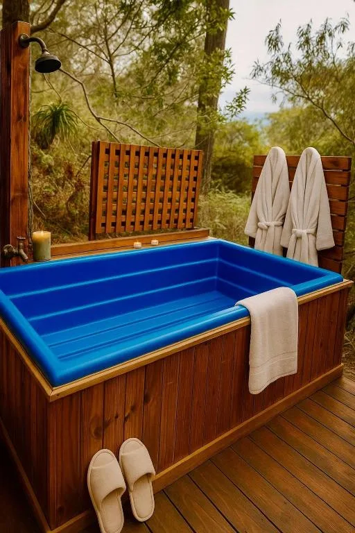 Wooden deck with blue soaking tub surrounded by forest greenery and trees