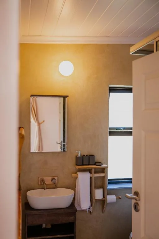 Modern bathroom with round white basin sink and warm ochre walls