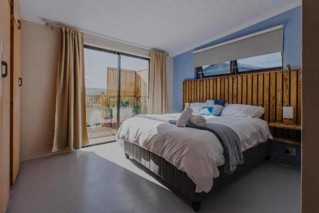 Bright bedroom with wooden headboard, ocean views through glass doors