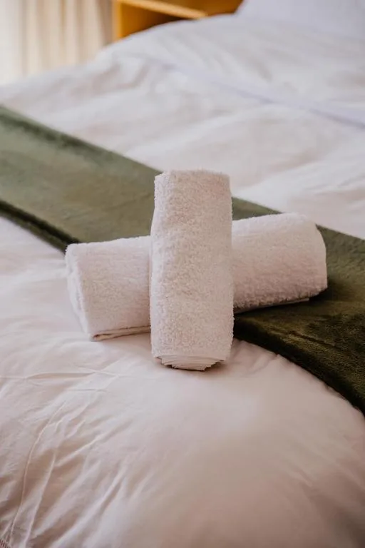 Rolled white towels arranged on a neatly made bed with pillows