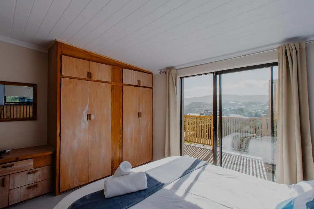 Spacious bedroom with wooden wardrobe and panoramic countryside views through glass doors