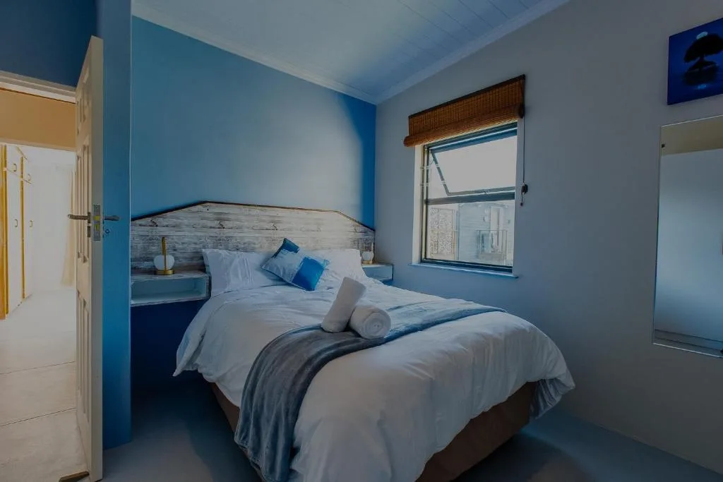 Bright blue bedroom with queen bed, white linens, and coastal decor