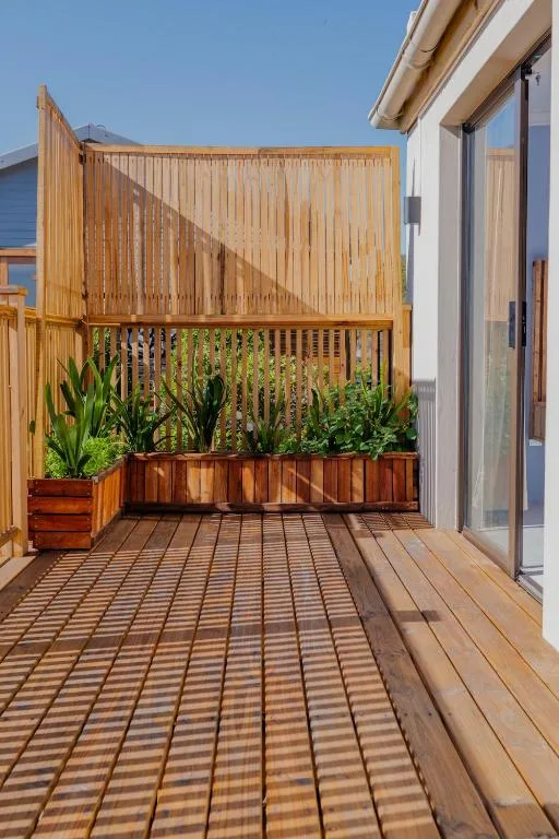 Wooden deck with planters and privacy screen beside modern building