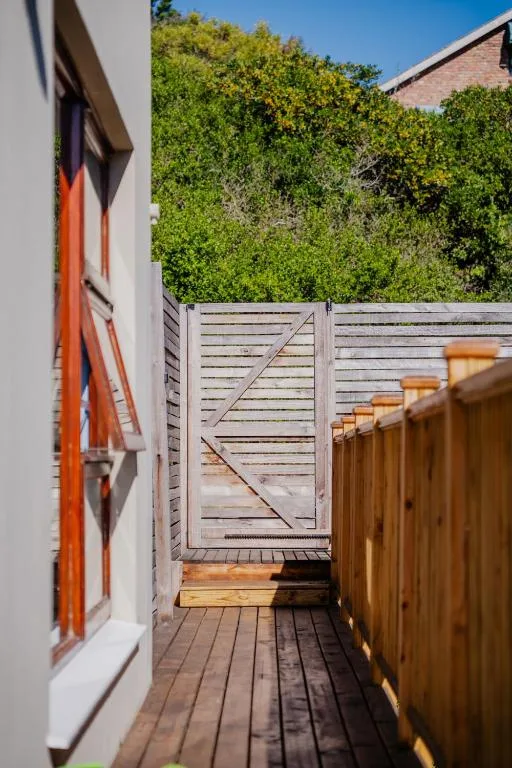 Wooden deck with white gate and lush green vegetation backdrop