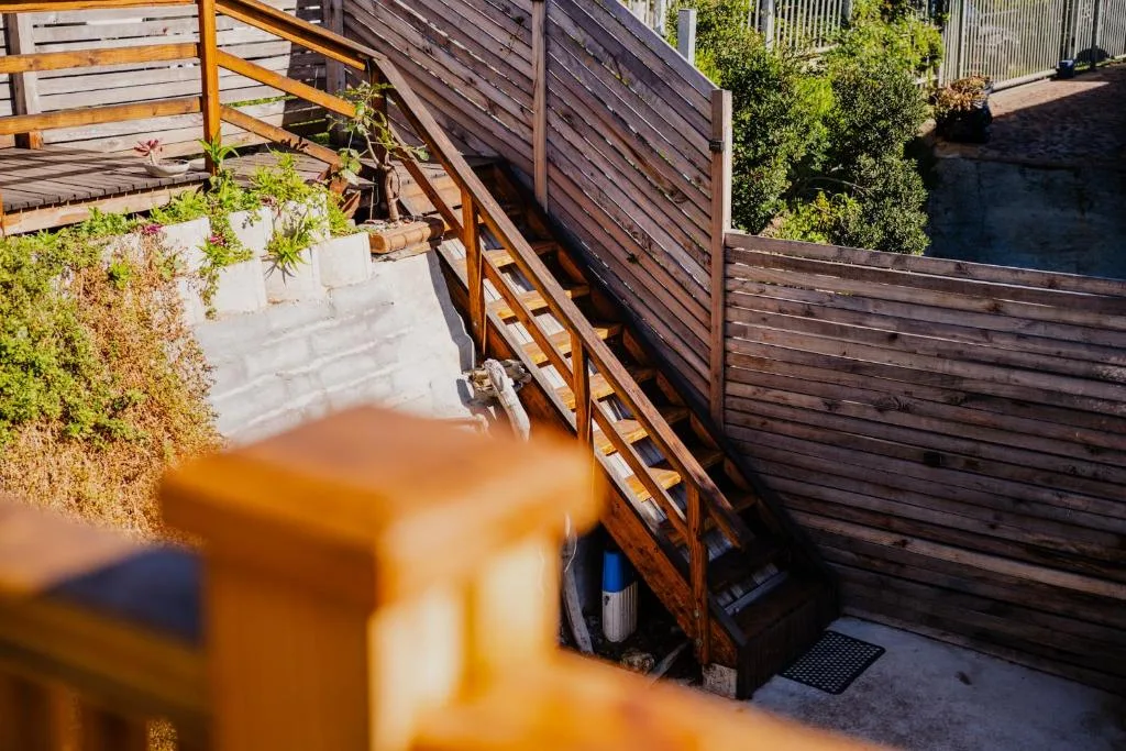 Wooden deck with stairs, railings, and potted plants overlooking garden area