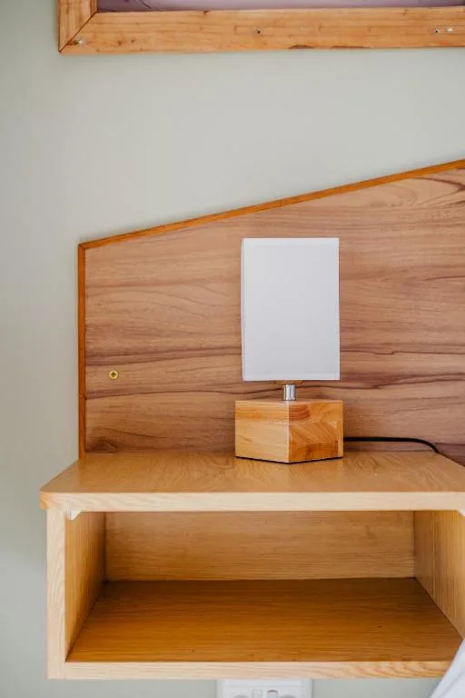 Wooden bedside table with minimalist lamp and white shade