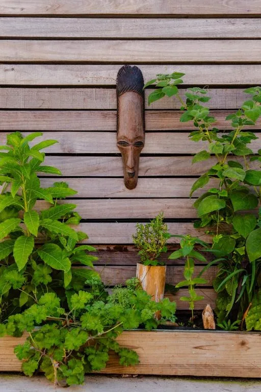 Wooden wall decoration with carved head mask and climbing plants