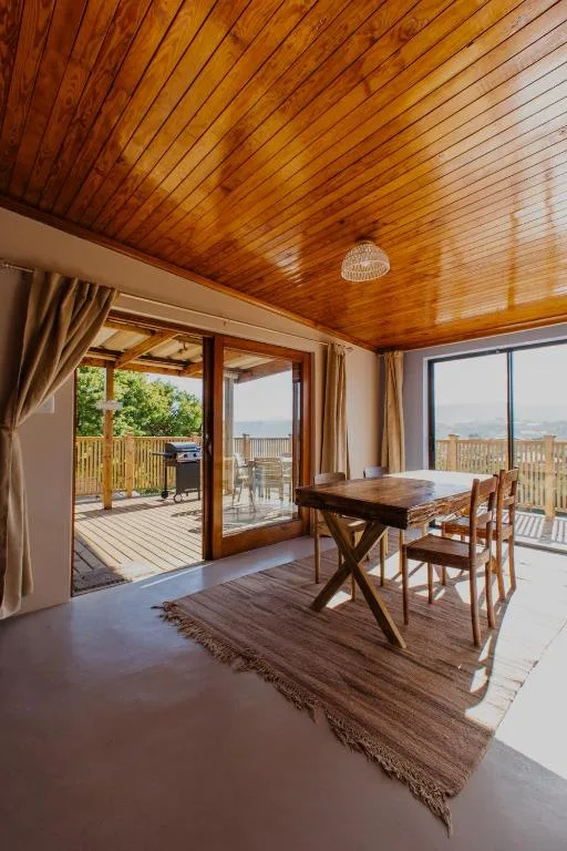 Dining area with wooden table, chairs, and scenic views through glass doors