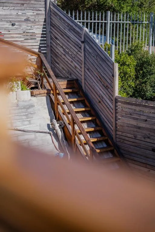 Wooden deck stairs with black railings beside property entrance