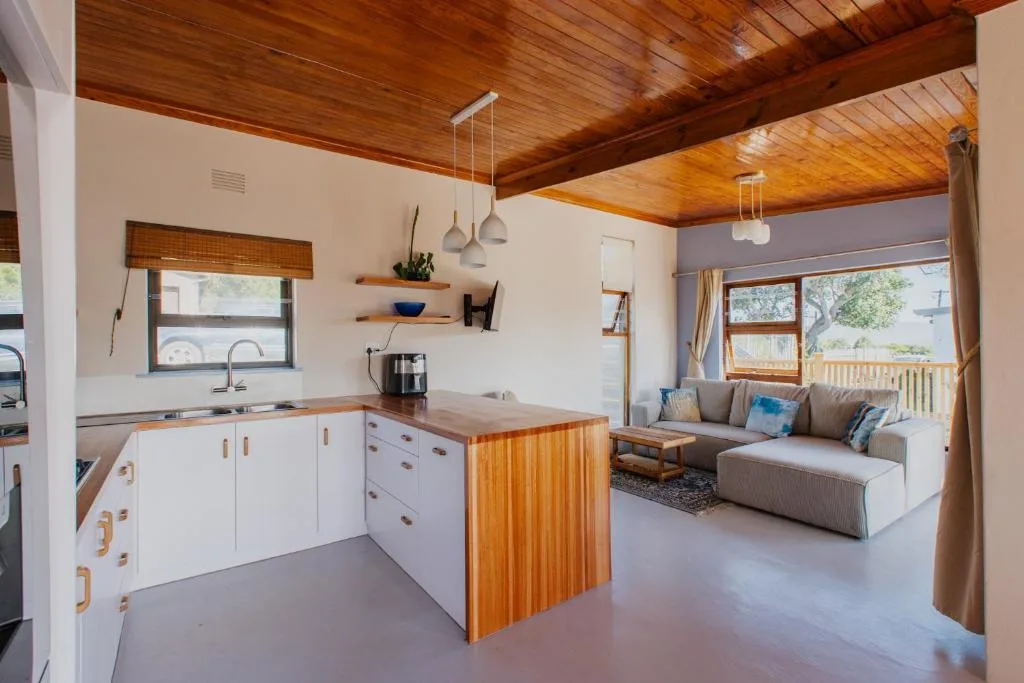 Modern kitchen with white cabinetry, wooden island, and wooden ceiling beams