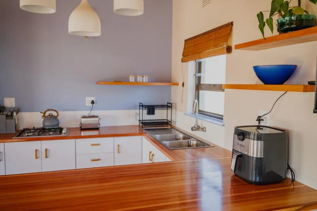Modern kitchen with white cabinetry, wooden countertops, and stainless steel appliances