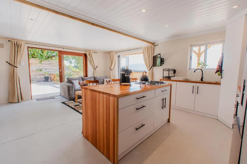 Modern kitchen with wooden island, white cabinetry, and open-plan living space