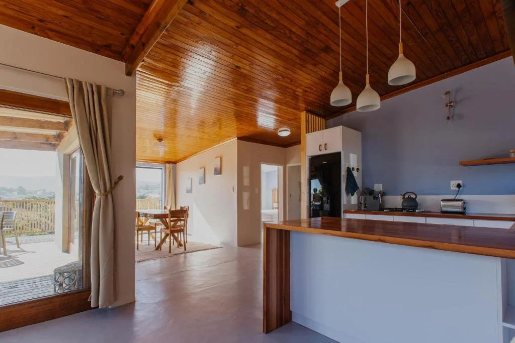 Modern kitchen with wooden ceiling, white cabinetry, and open-plan layout