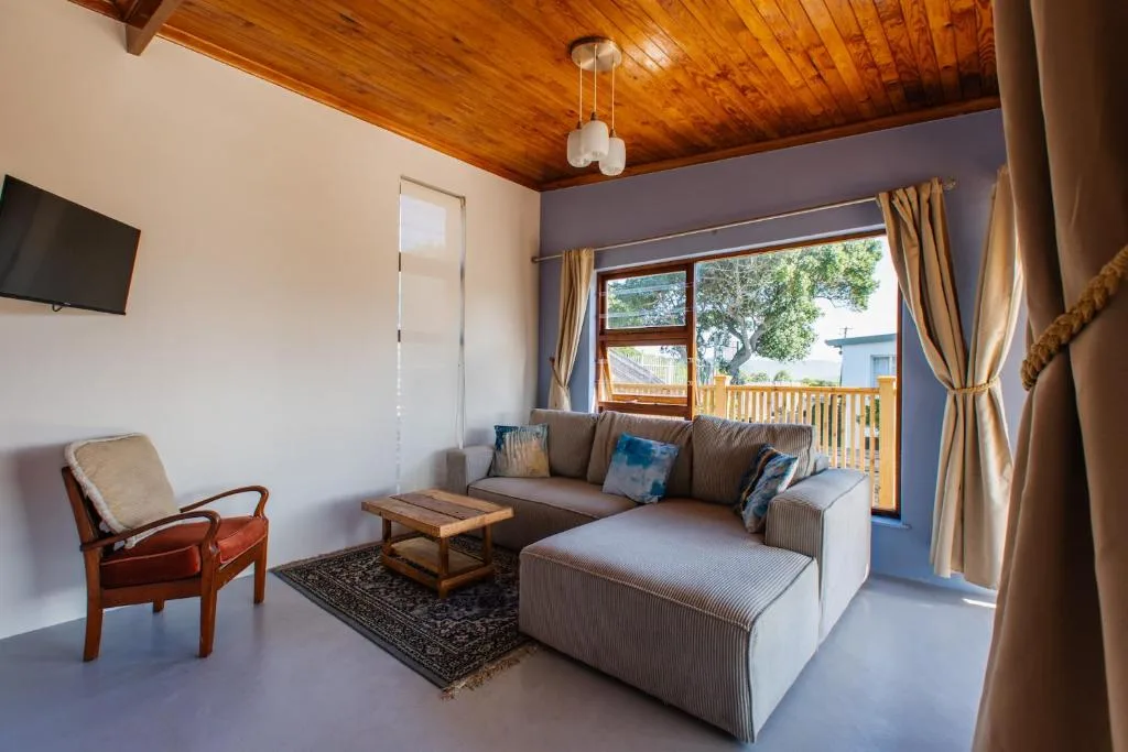 Spacious living room with gray sectional sofa, wooden ceiling, and deck access