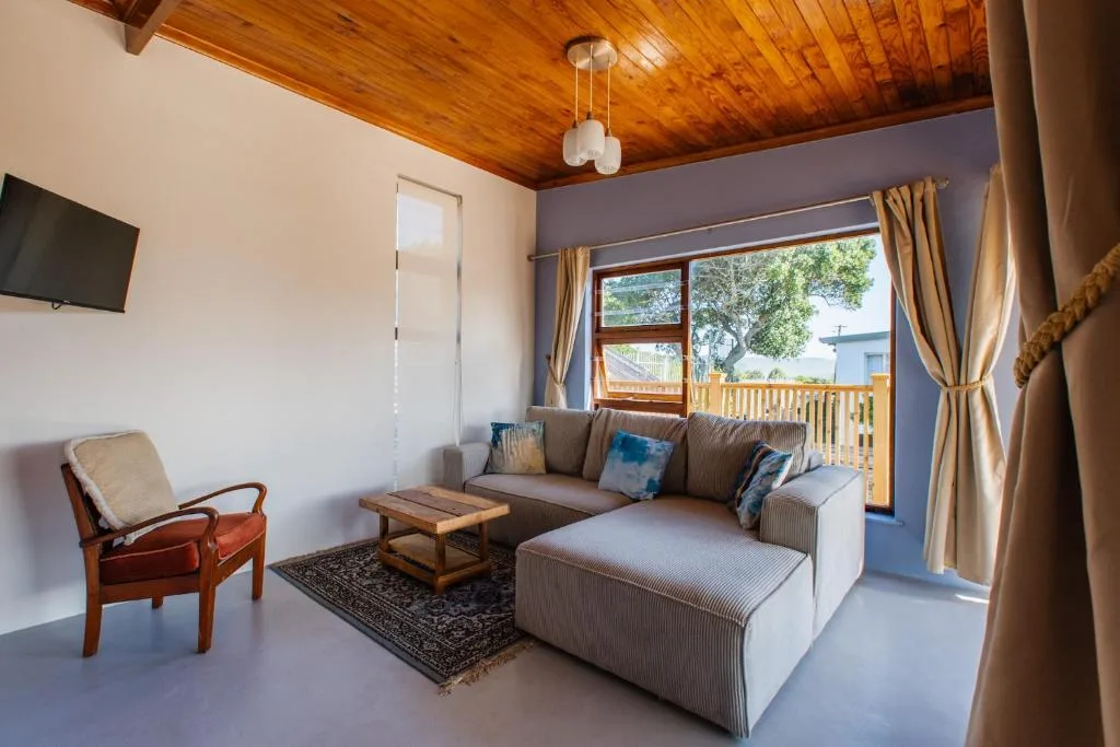 Spacious lounge with gray sectional sofa, wooden ceiling, and deck access