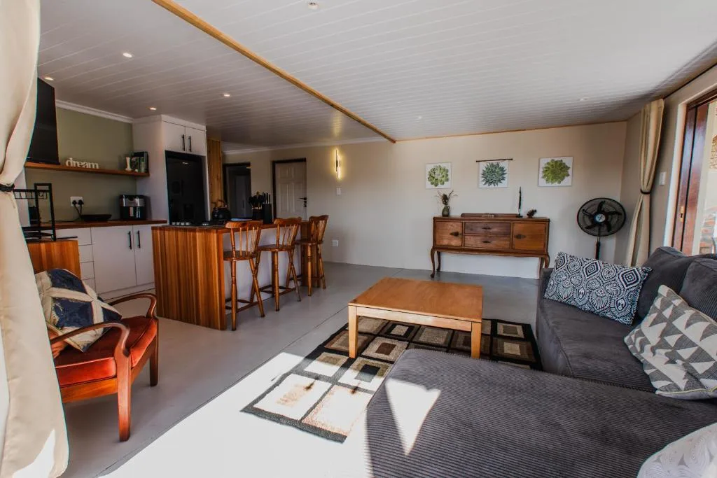 Open-plan lounge with sofa, dining area, and kitchen visible in background