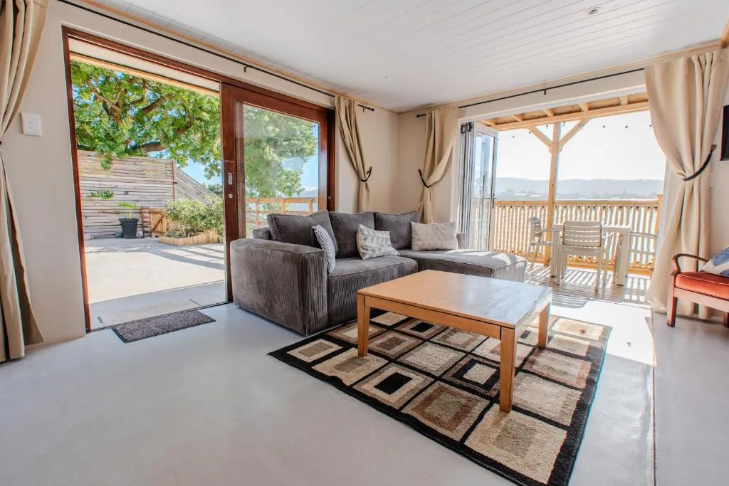 Bright lounge with gray sofa, wooden table, and expansive deck views beyond