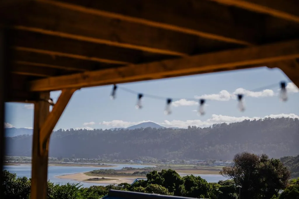 Scenic lagoon and mountain vista framed by wooden pergola structure