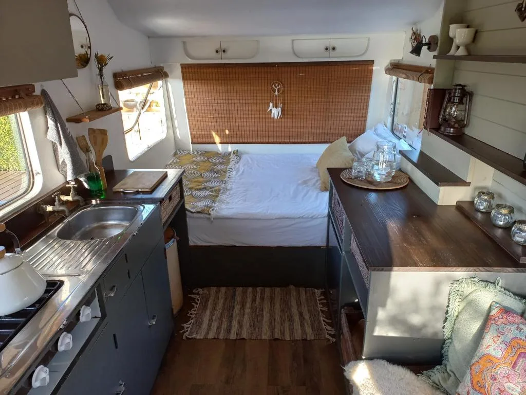 Compact bedroom in caravan with bed, kitchenette, and natural light
