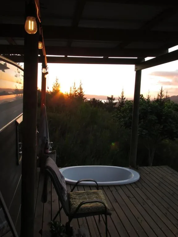 Hot tub on wooden deck at sunset with forest and mountain views