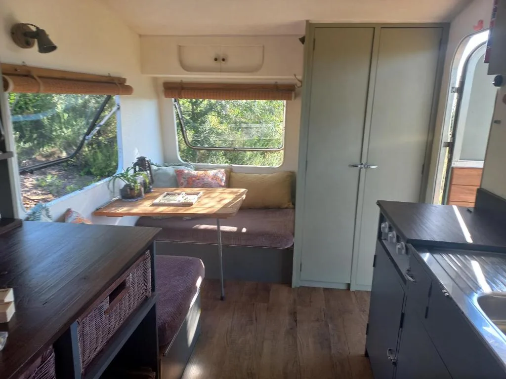 Compact caravan lounge with seating area and large windows overlooking garden