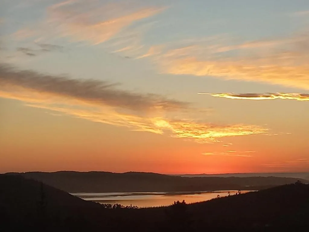 Scenic sunset over lagoon with golden sky and forested hills