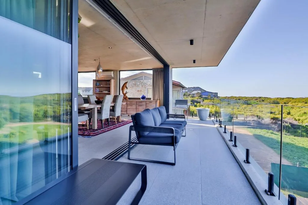 Modern covered deck with contemporary seating overlooking scenic green landscape