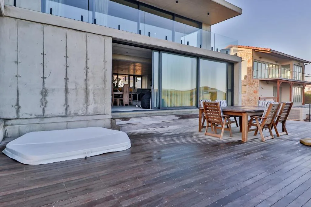 Spacious wooden deck with outdoor seating and hot tub overlooking garden route landscape