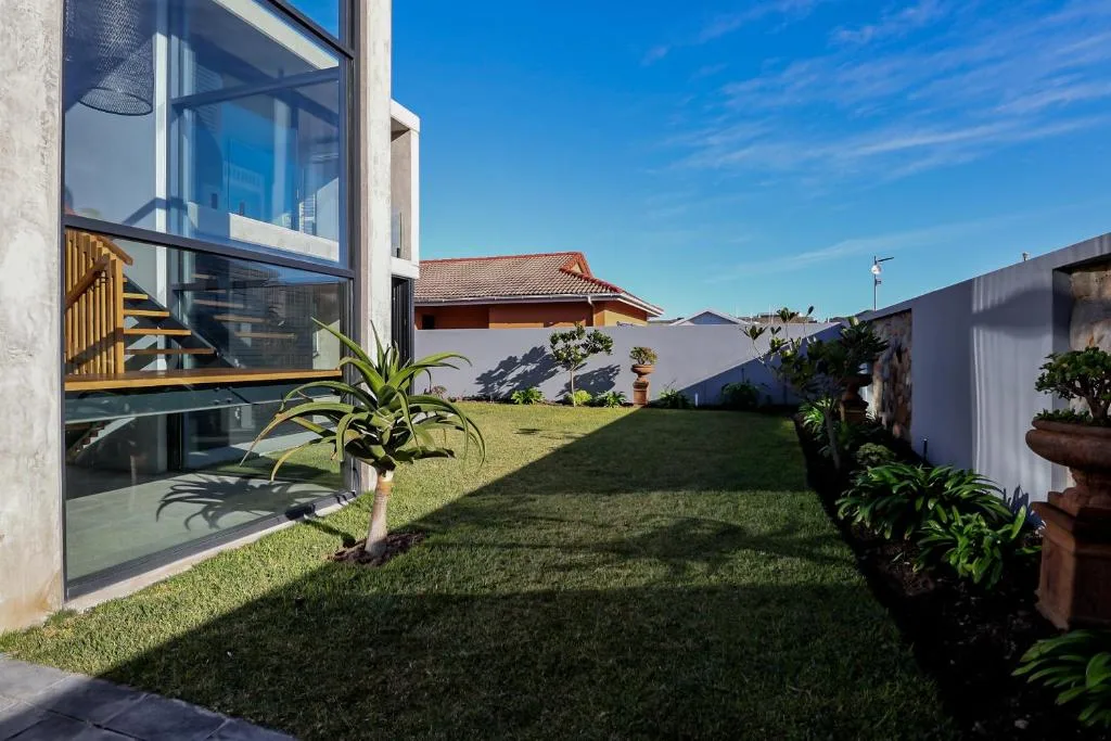 Modern beachfront home with manicured lawn and potted plants
