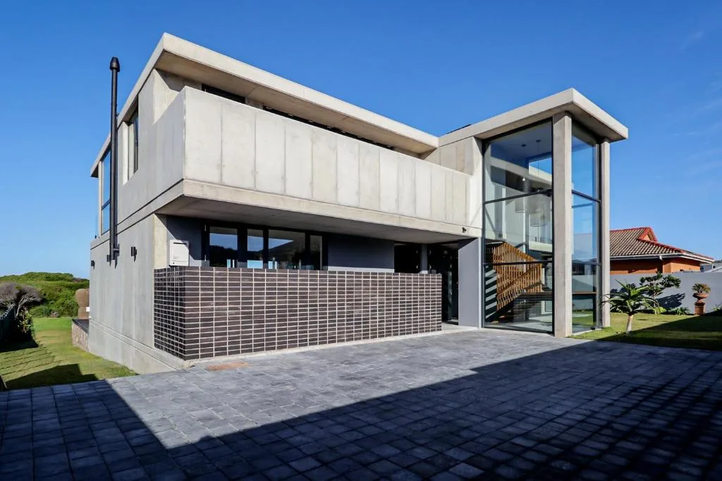 Modern two-story beach house with cream facade and black tile accents
