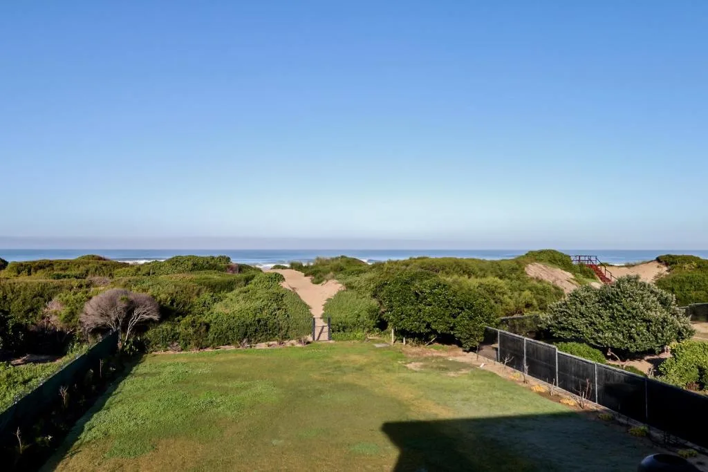 Scenic coastal view from property overlooking beach, dunes, and ocean horizon