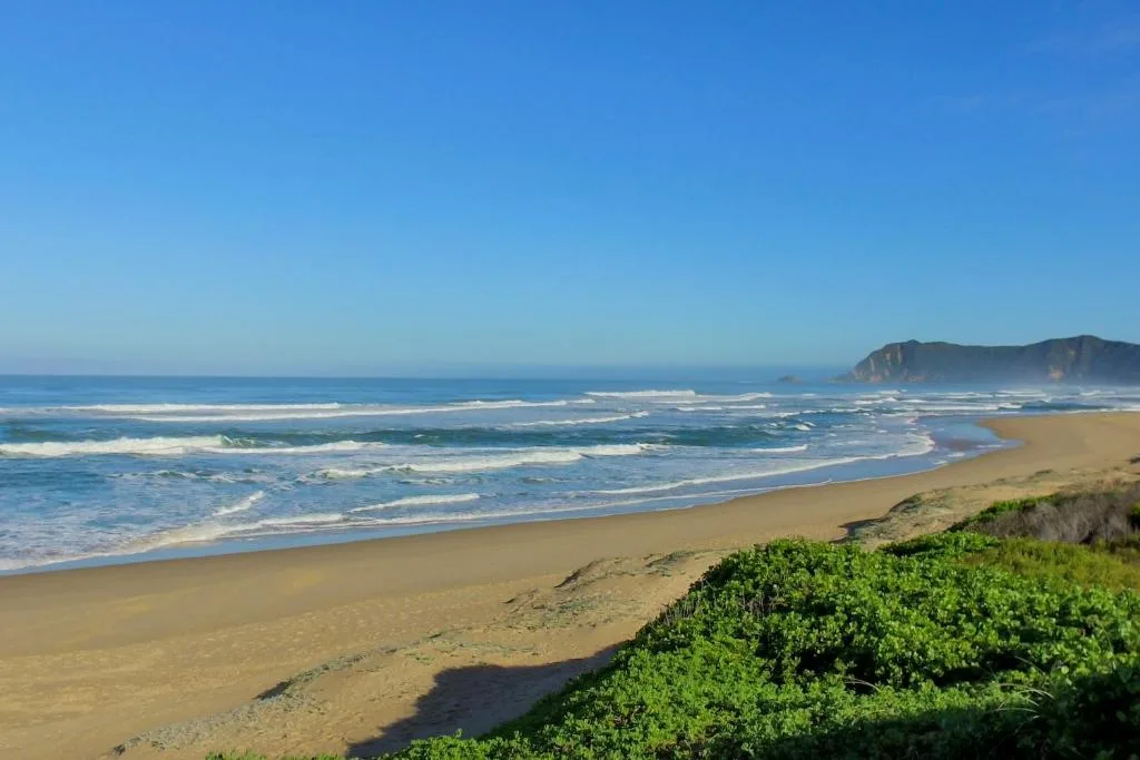 Scenic beach view with sand, waves, and distant rocky headlands